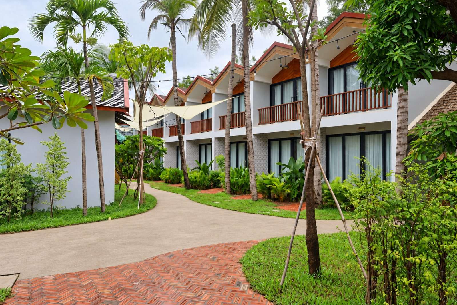 Guest rooms seen from the drive, palms and young trees along a brick path